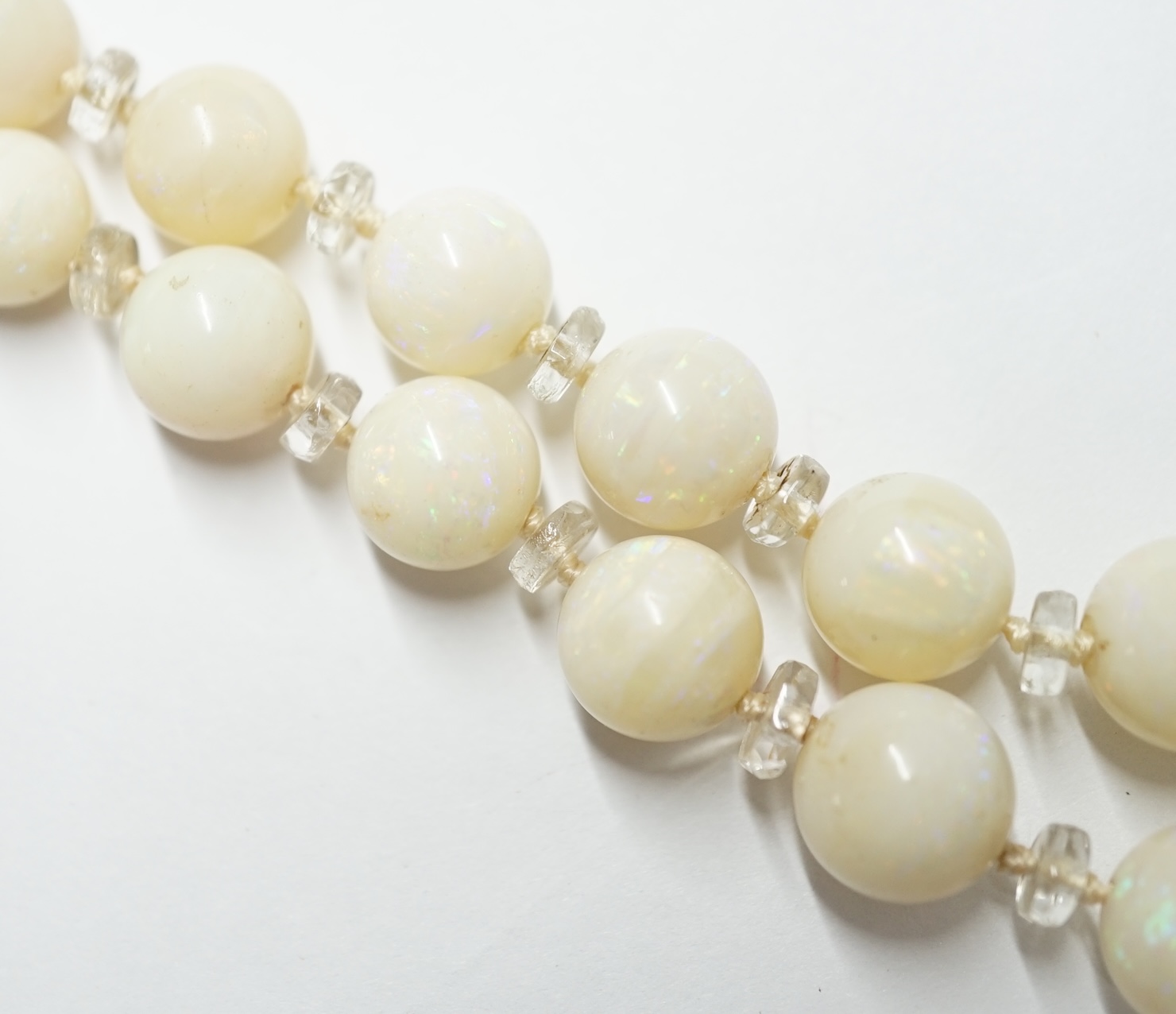 A single strand graduated white opal circular bead necklace, with paste? spacers and white metal clasp, 58cm. Condition - fair